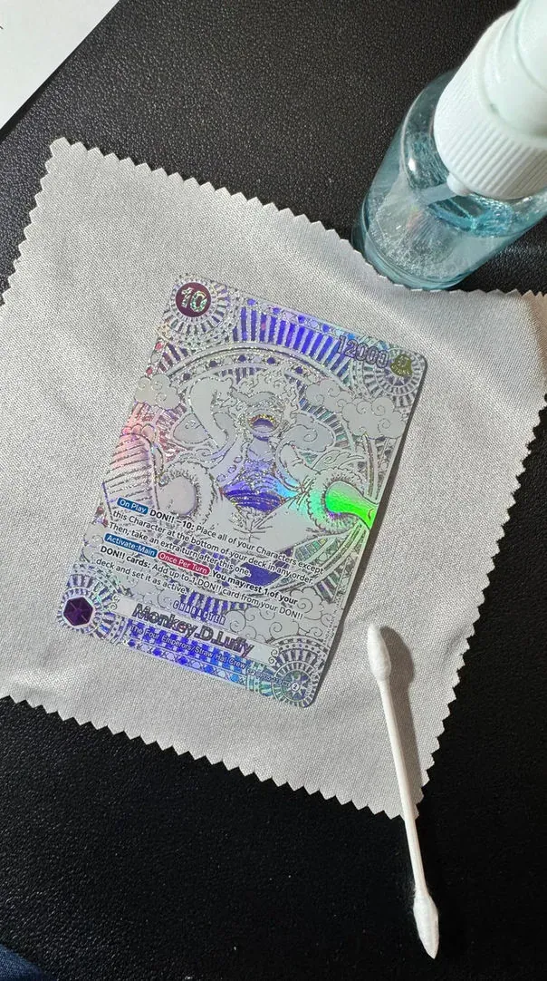 Trading card on a microfibre cloth alongside a cleaning bottle on the conservation bench